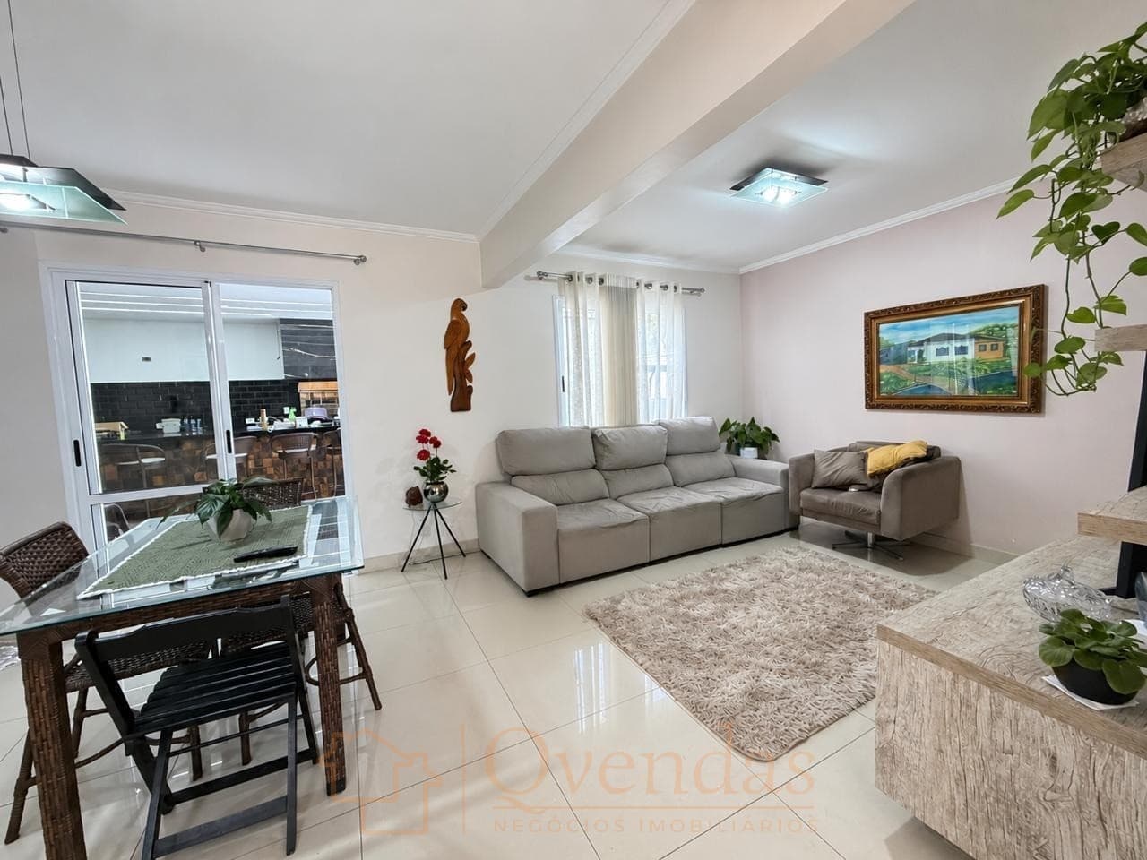 Sala de estar e jantar integrada com piso claro, sofá cinza e mesa de jantar.